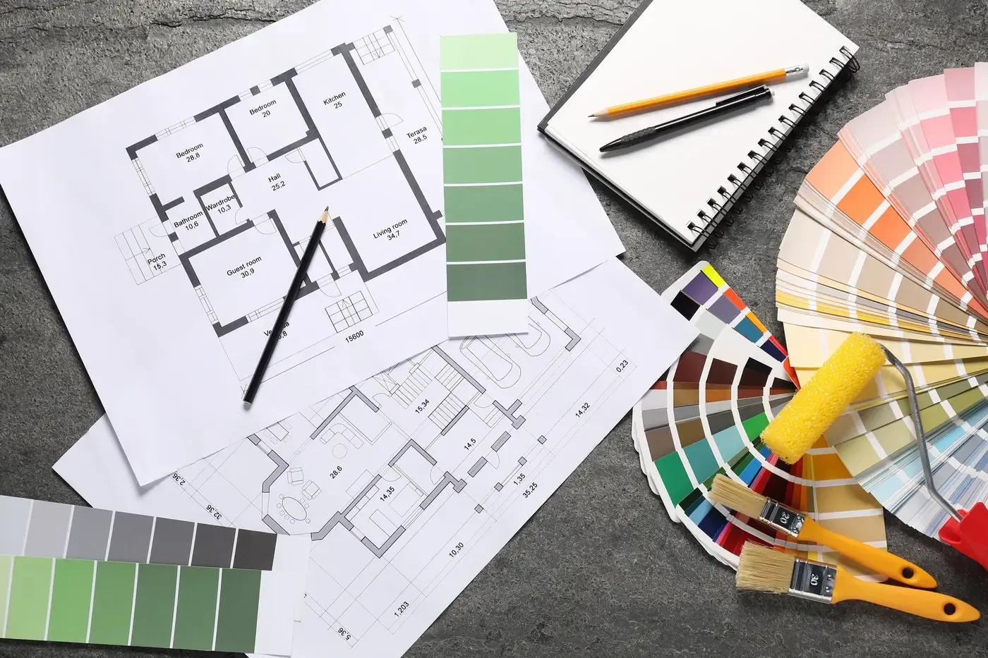 Paint colour cards, a fan deck and brushes laid out over house floor plans